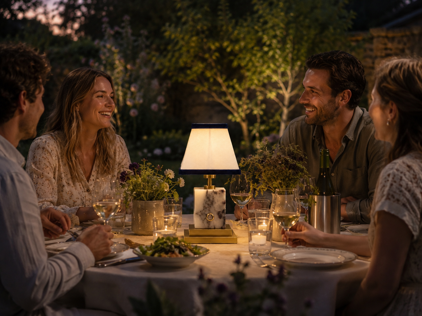An elegant and stylish dressed table in a British garden on a summers evening with a marble rechargeable lamp centrepiece