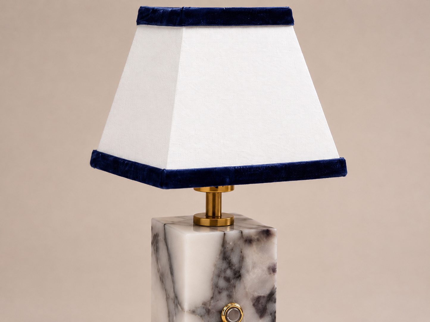 Lamp with marble base and white shade with blue trim on a beige background